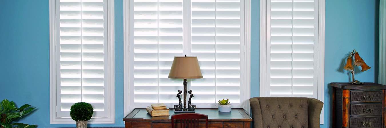White interior shutters on windows on a bright blue wall